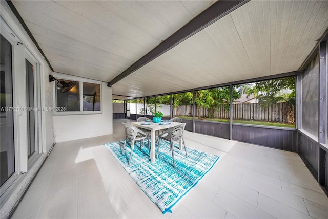 sunroom / solarium with outdoor dining space and beam ceiling