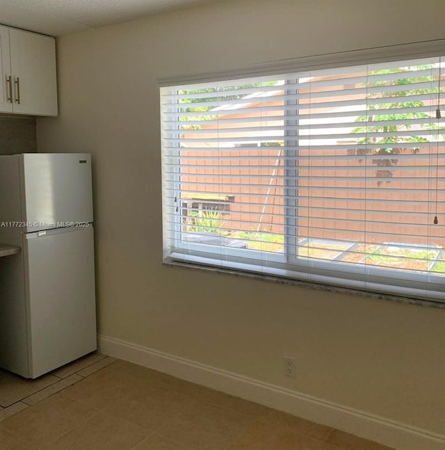 3190 NW 66th Dr, Fort Lauderdale, FL 33309 - kitchen with freestanding refrigerator, light tile patterned flooring, white cabinets, and baseboards