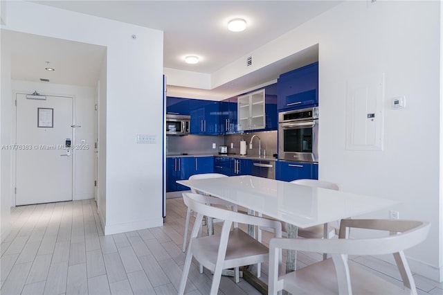 3101 Bayshore Dr Unit 603, Fort Lauderdale, FL 33304 - kitchen with appliances with stainless steel finishes, electric panel, decorative backsplash, light wood finished floors, and blue cabinets