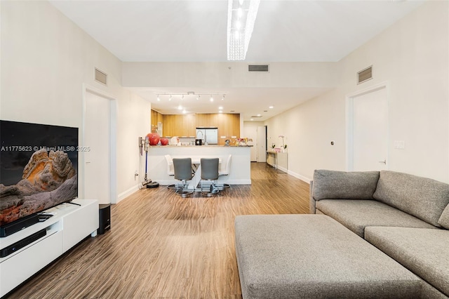 living room with baseboards, visible vents, and light wood-type flooring