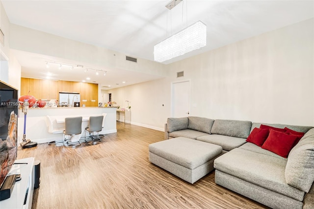 living room with baseboards, visible vents, and light wood-type flooring