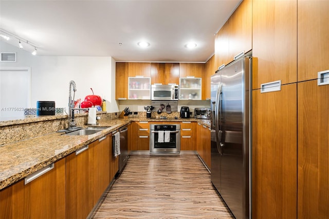 kitchen featuring modern cabinets, visible vents, brown cabinetry, and stainless steel appliances