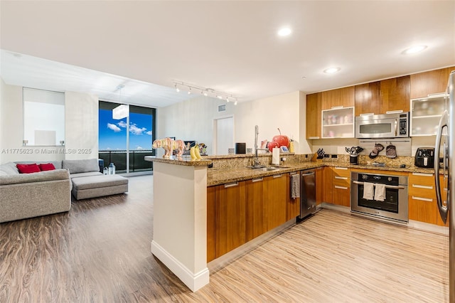 kitchen with a peninsula, modern cabinets, appliances with stainless steel finishes, and brown cabinetry