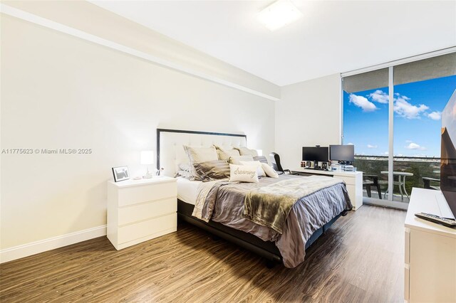 bedroom featuring floor to ceiling windows, baseboards, access to outside, and wood finished floors