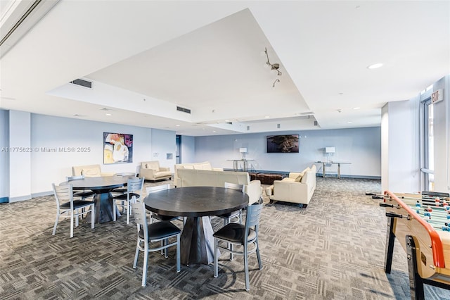 dining space with carpet floors, a tray ceiling, and visible vents