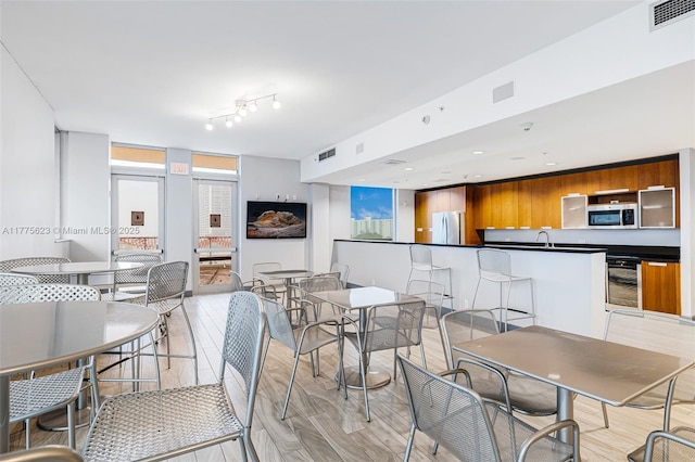 dining area featuring visible vents, light wood-type flooring, and beverage cooler