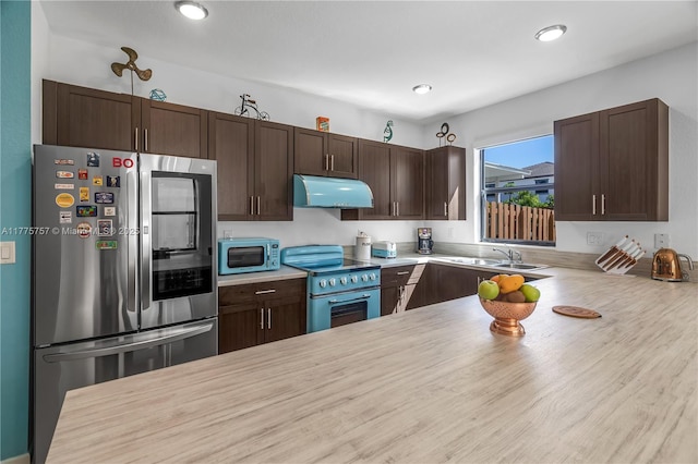 kitchen featuring light countertops, appliances with stainless steel finishes, dark brown cabinetry, and under cabinet range hood