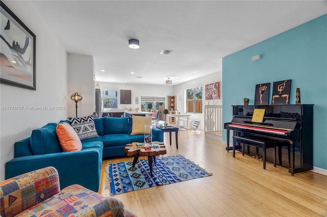 living room with baseboards, a healthy amount of sunlight, visible vents, and light wood-type flooring