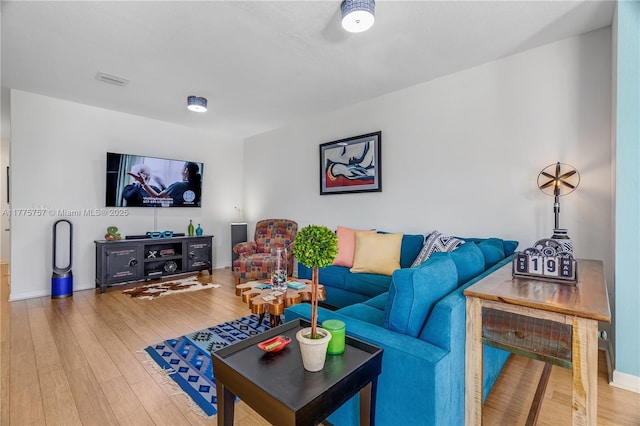 living room featuring baseboards, wood finished floors, and visible vents