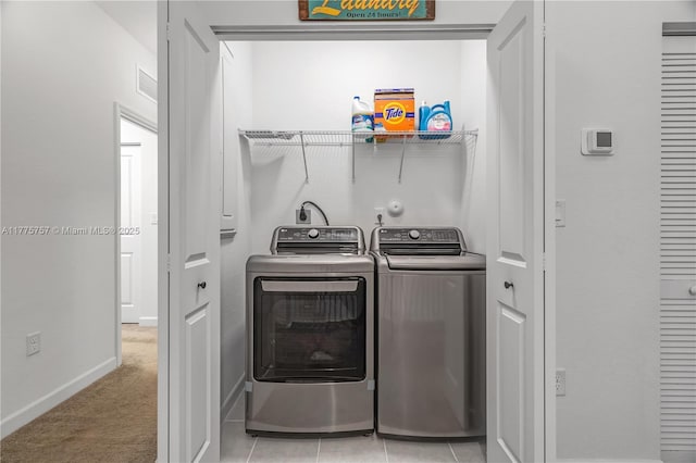 washroom featuring laundry area, visible vents, washing machine and dryer, baseboards, and light colored carpet