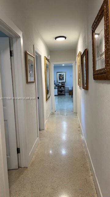 hall with baseboards and light speckled floor