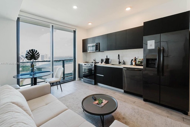398 NE 5th St Unit 1408, Miami, FL 33132 - kitchen featuring dark cabinetry, appliances with stainless steel finishes, light wood-style floors, and decorative backsplash