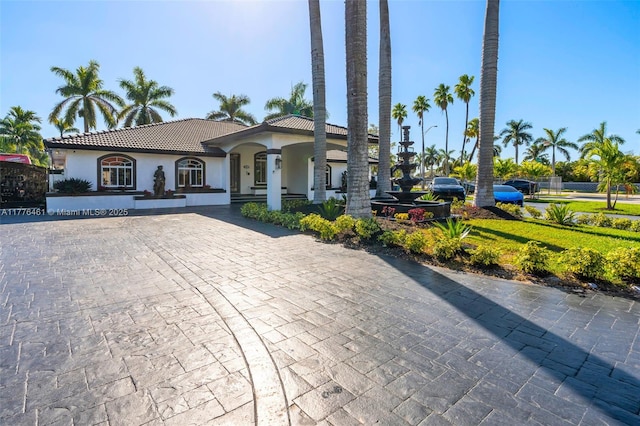 mediterranean / spanish-style house with a tile roof, decorative driveway, and stucco siding