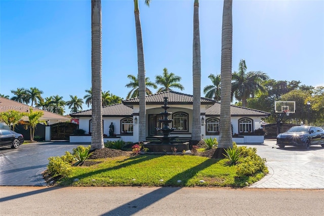 mediterranean / spanish-style house with a tile roof, stucco siding, and fence