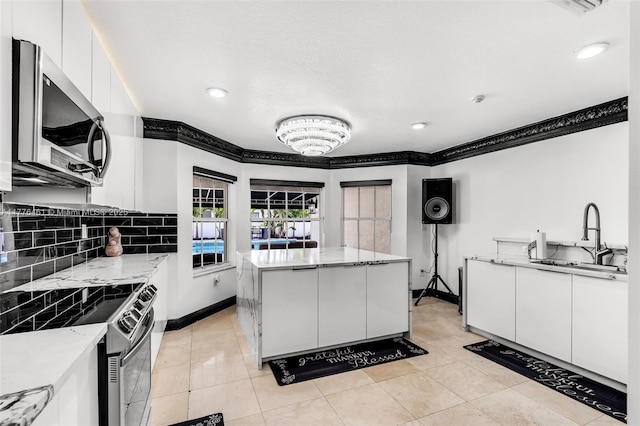 kitchen with ornamental molding, white cabinets, stainless steel appliances, and decorative backsplash