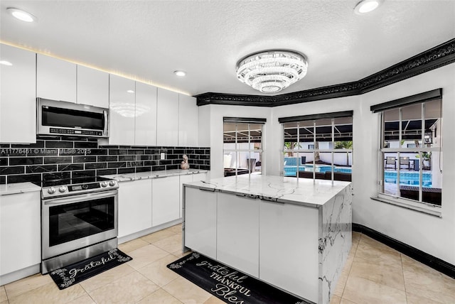kitchen with white cabinetry, a kitchen island, stainless steel appliances, and tasteful backsplash