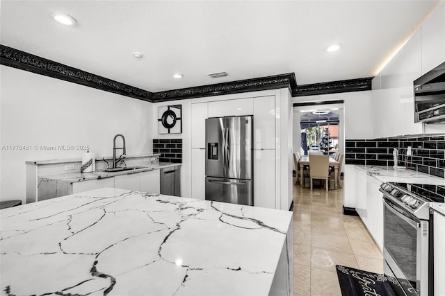 kitchen with decorative backsplash, white cabinets, visible vents, stainless steel appliances, and a sink
