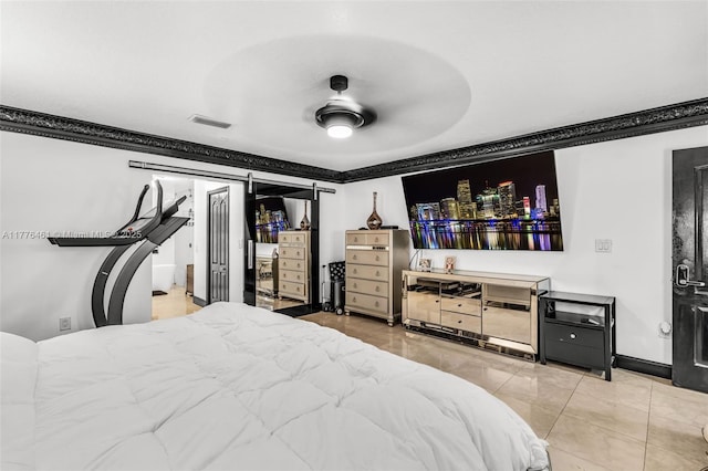 bedroom with a barn door, ornamental molding, baseboards, and visible vents