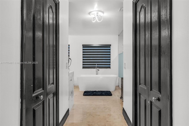 bathroom with baseboards, a freestanding bath, and visible vents