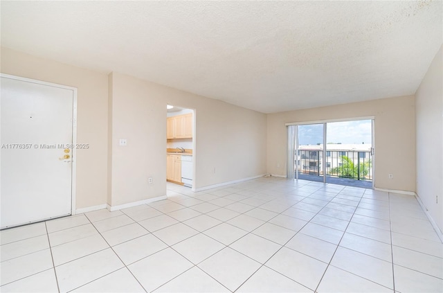 unfurnished room featuring baseboards, a textured ceiling, a sink, and light tile patterned floors