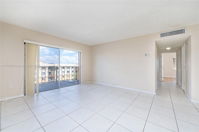 unfurnished room featuring light tile patterned flooring, baseboards, a textured ceiling, and visible vents