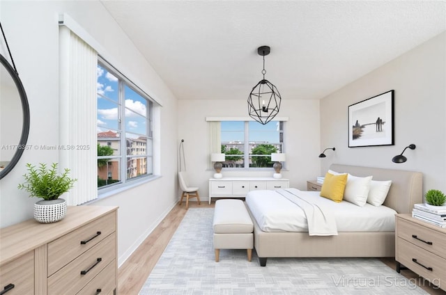 bedroom with baseboards, light wood-style flooring, and a chandelier