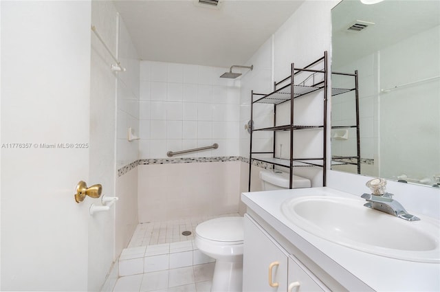 full bathroom with visible vents, toilet, tiled shower, and vanity