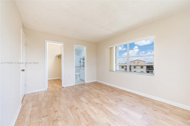 empty room with a textured ceiling, baseboards, and wood finished floors