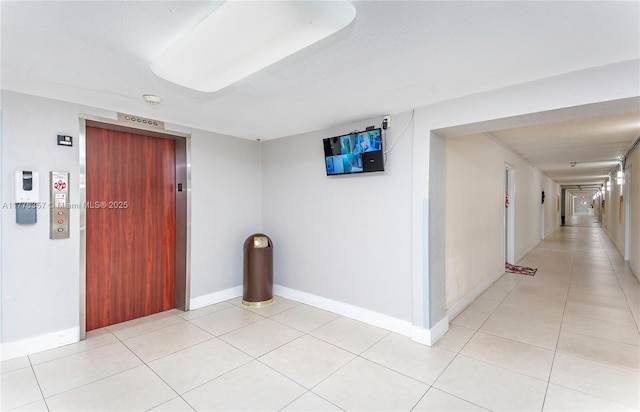 interior space featuring elevator, baseboards, and light tile patterned flooring