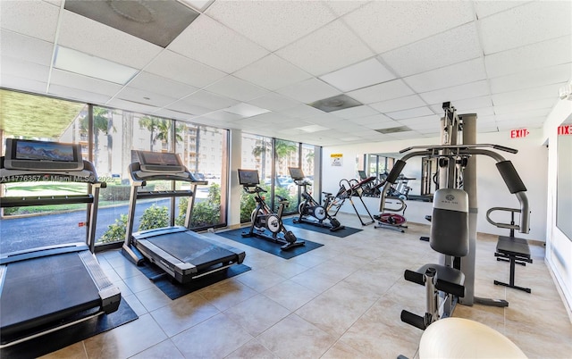 gym with a wall of windows, baseboards, and a paneled ceiling