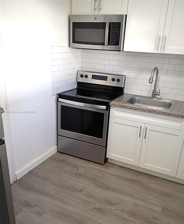 kitchen featuring white cabinetry, a sink, appliances with stainless steel finishes, and wood finished floors