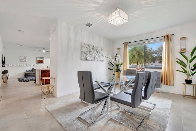 tiled dining space featuring baseboards, visible vents, and ceiling fan with notable chandelier