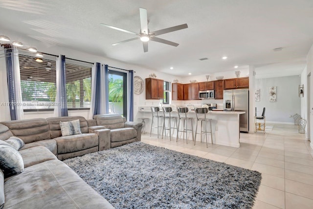 living area with recessed lighting, light tile patterned floors, baseboards, a textured ceiling, and a ceiling fan