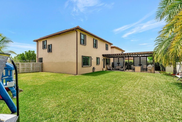 back of house featuring a pergola, a lawn, stucco siding, and fence