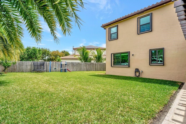 view of yard featuring a trampoline and a fenced backyard