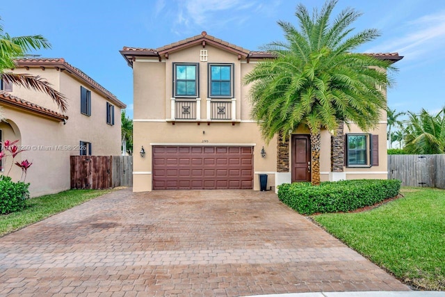 mediterranean / spanish house featuring stucco siding, an attached garage, fence, and driveway