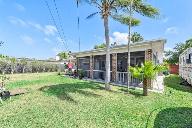rear view of house featuring brick siding, a yard, a sunroom, and a fenced backyard