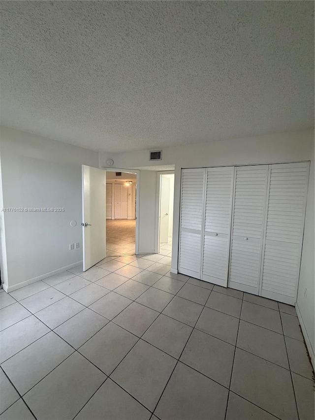 8335 SW 152nd Ave Unit B-106, Miami, FL 33193 - unfurnished bedroom with a textured ceiling, tile patterned floors, and a closet