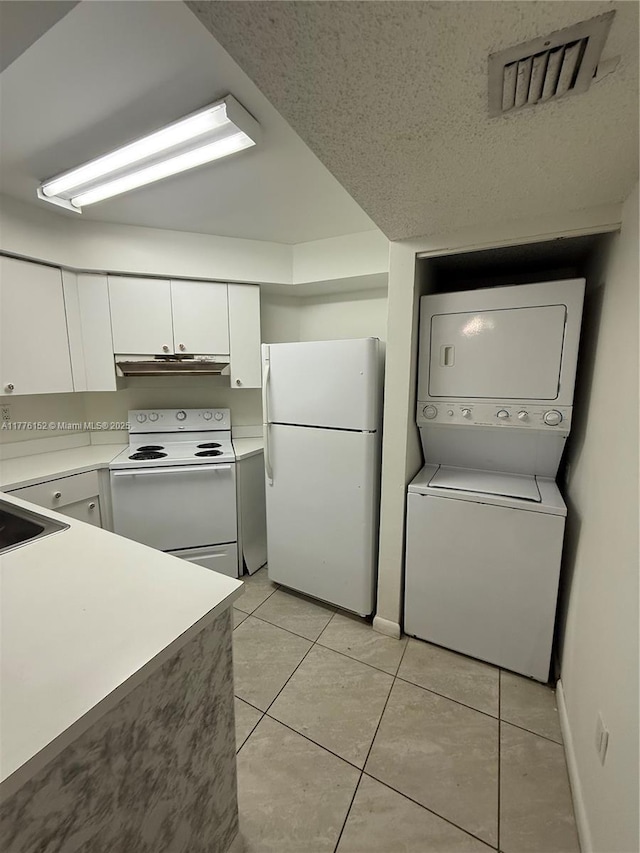 8335 SW 152nd Ave Unit B-106, Miami, FL 33193 - kitchen with white appliances, stacked washer and clothes dryer, under cabinet range hood, white cabinets, and light tile patterned flooring