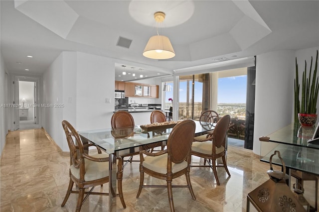 dining space with a tray ceiling, baseboards, visible vents, and marble finish floor