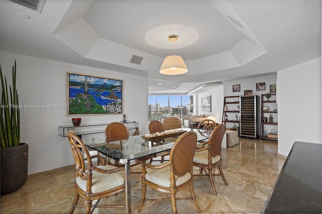 dining space featuring a tray ceiling, baseboards, marble finish floor, and visible vents