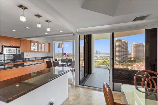 kitchen with stainless steel microwave, backsplash, hanging light fixtures, visible vents, and a view of city