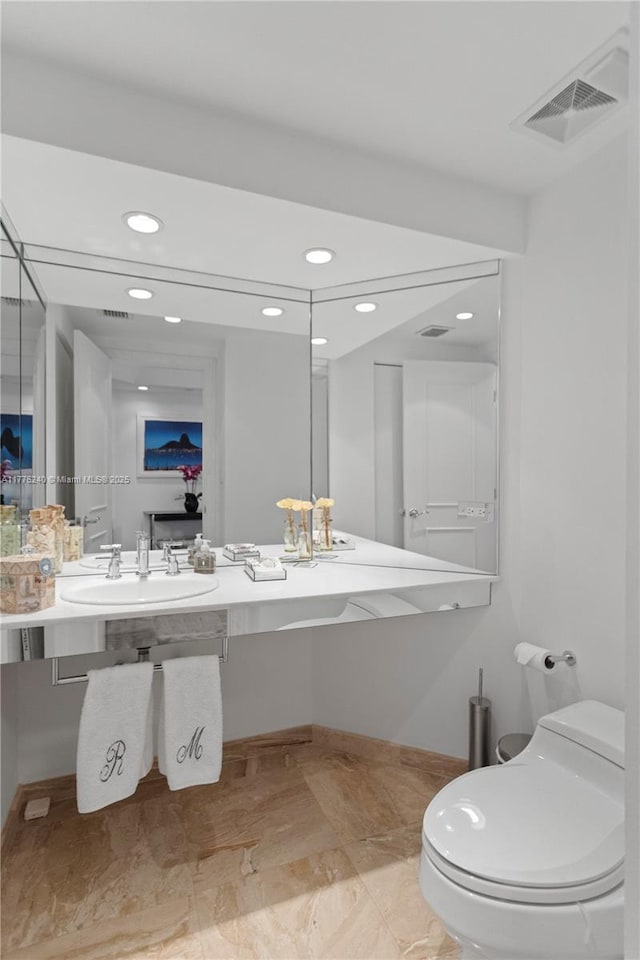 bathroom featuring recessed lighting, toilet, marble finish floor, a sink, and visible vents