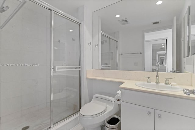 bathroom featuring toilet, vanity, a stall shower, and visible vents