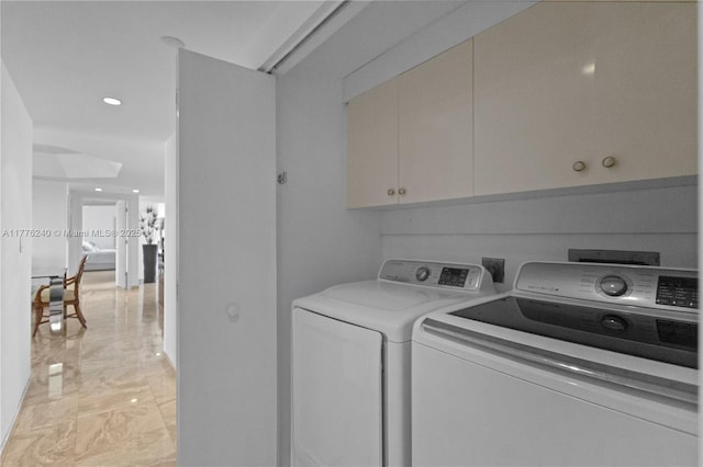 clothes washing area with marble finish floor, washing machine and clothes dryer, and cabinet space