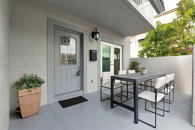 entrance to property with french doors, outdoor dining area, and stucco siding