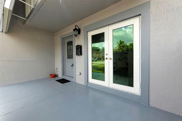 entrance to property with french doors, a patio area, and stucco siding