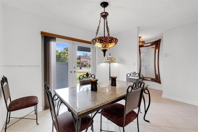 dining space featuring a textured ceiling, baseboards, light tile patterned flooring, and french doors