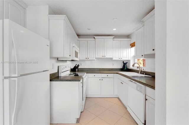 kitchen featuring a sink, white cabinetry, dark countertops, and white appliances