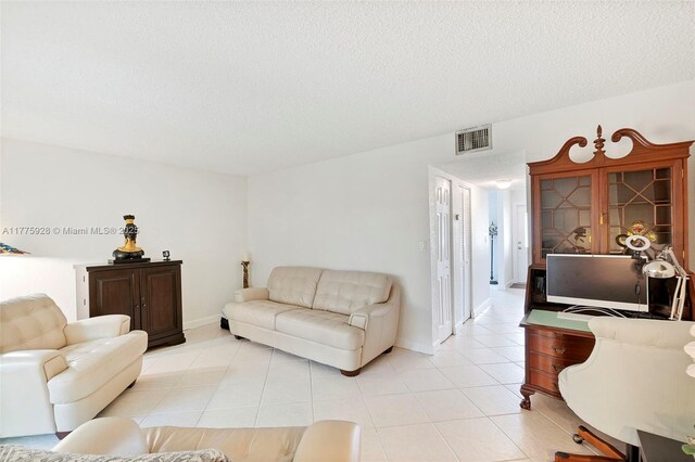 living area with baseboards, a textured ceiling, visible vents, and light tile patterned floors
